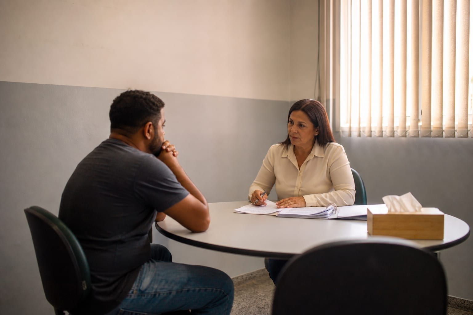 Atendimento reservado entre funcionária da escola e responsável, com contratos sobre a mesa