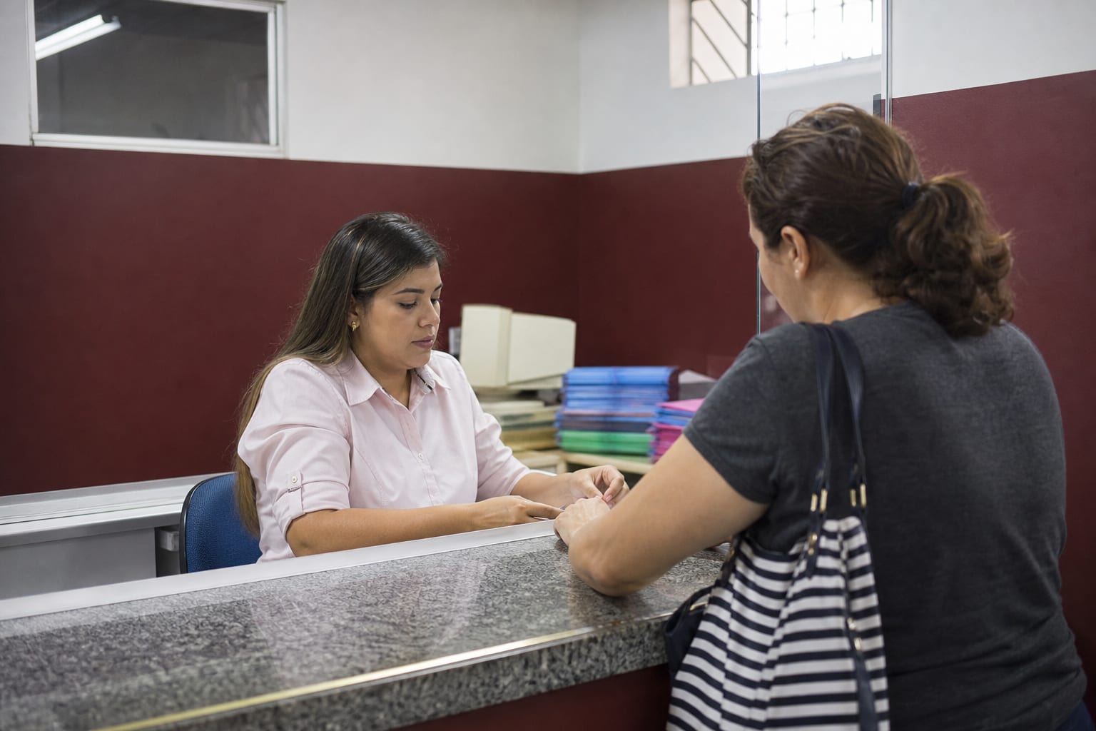 Atendimento no balcão da tesouraria de um colégio, com piso de granilite e parede com barra pintada